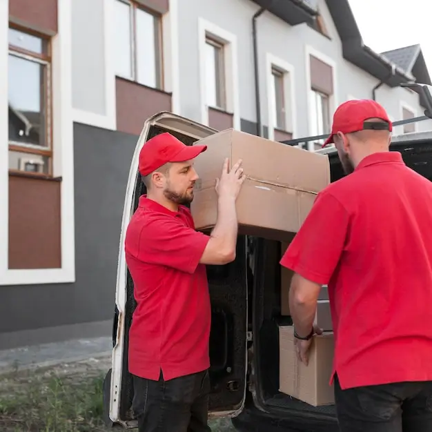 Zwei Liefermänner in Rot laden Kartons aus Transporter.